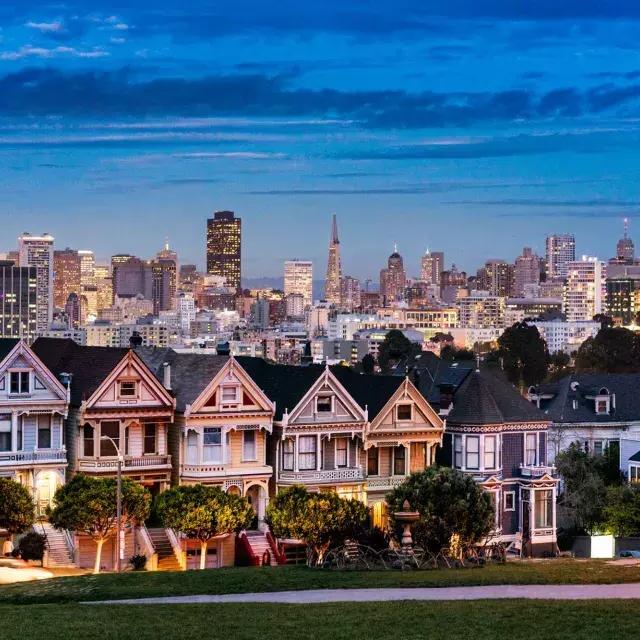 The famous Painted Ladies of Alamo Square are pictured before the San Francisco skyline at twilight.